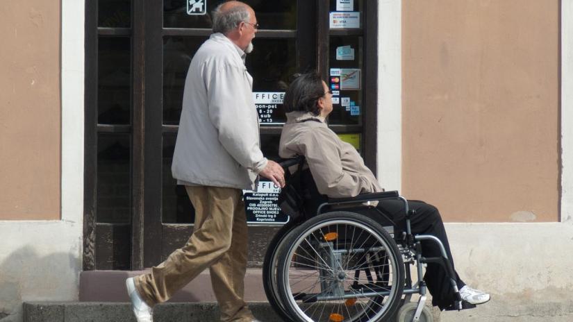 Asystent prowadzący osobę niepełnosprawną na wózku. Fot. pixabay.com