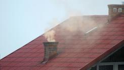 Dymiący komin na dachu budynku mieszkalnego.