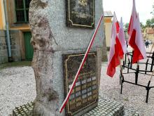 Szarfa pod pomnikiem Wolność Krzyżami się Mierzy.